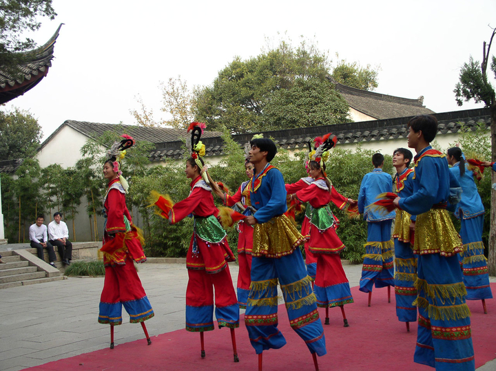 a group of performers in colorful costumes dancing on stilts 