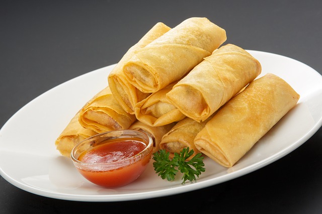 spring rolls served with sauce and a coriander leaf as garnish