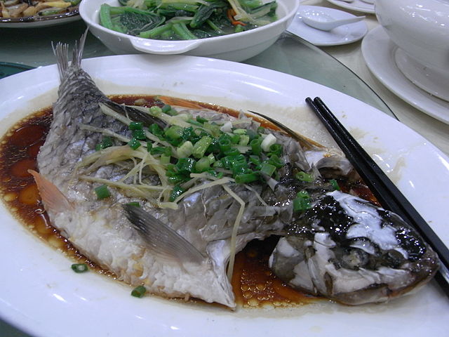 whole steamed fish topped with chopped onion leaves