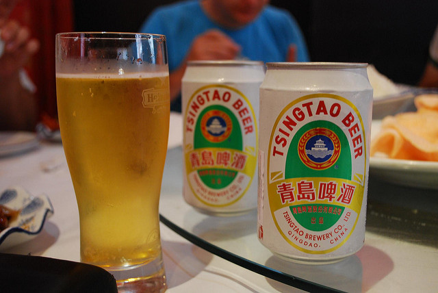 a glass filled with two cans of tsingtao beer